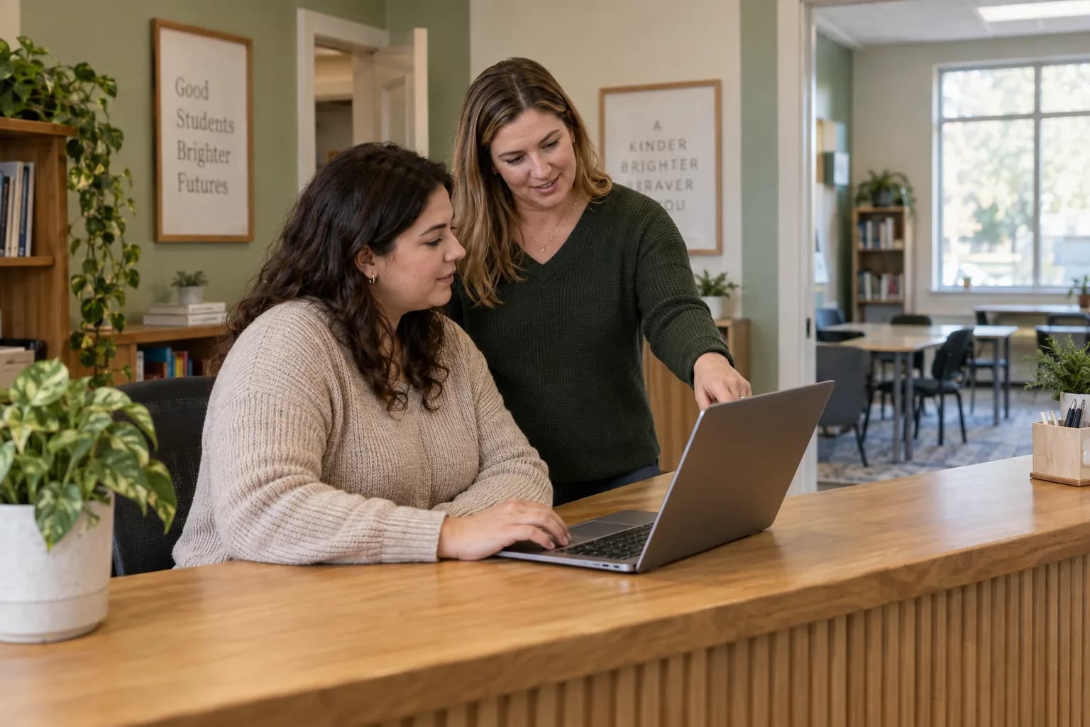 Two learning-center staff members practicing a new routine together on a laptop at the front desk.